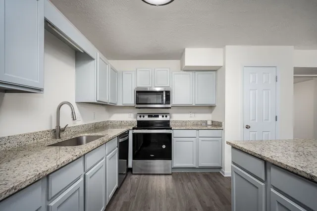 a kitchen with stainless steel appliances granite countertop a sink stove and refrigerator