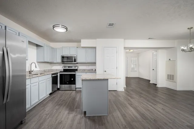 a kitchen with granite countertop a refrigerator oven a sink dishwasher and a stove with wooden floor