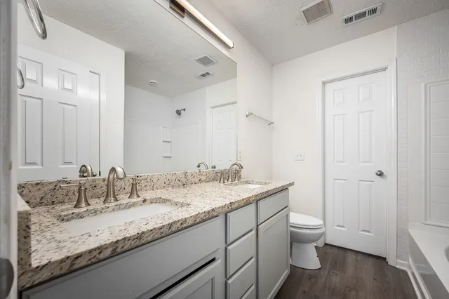 a bathroom with a granite countertop sink a toilet and a mirror