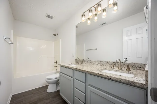 a bathroom with a granite countertop sink a toilet and a large mirror