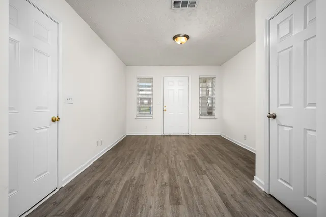 an empty room with wooden floor and windows