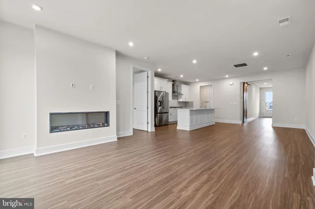 a view of a kitchen with a fridge and wooden floor