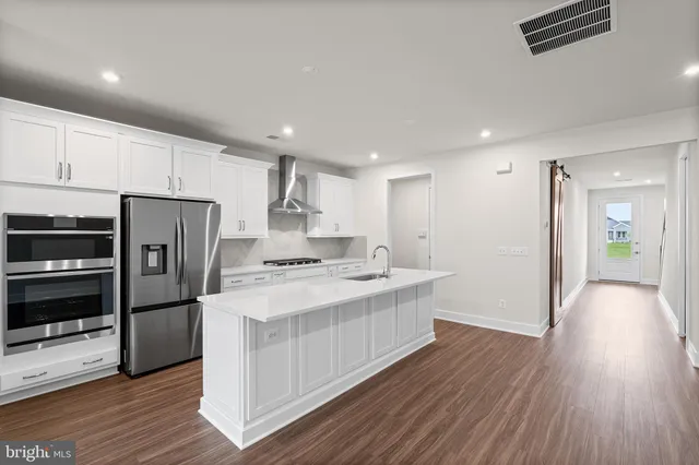 a kitchen with a refrigerator a sink and wooden floor