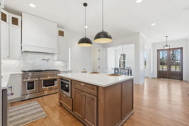 a hall with kitchen island a stove a sink a dining table and chairs