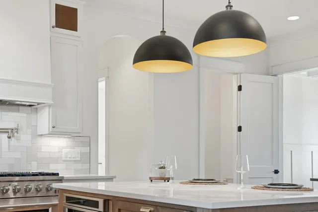 a kitchen with stainless steel appliances a stove a sink a refrigerator wooden floor and white cabinets