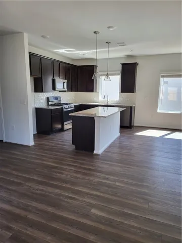 a large kitchen with stainless steel appliances a large counter top a stove and a wooden floors