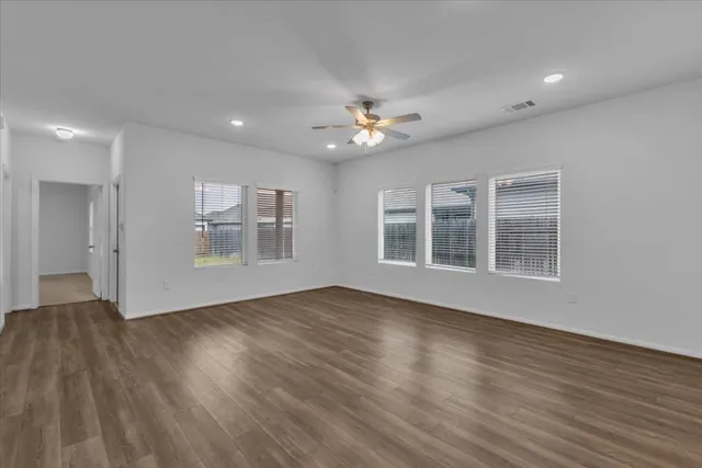 a view of an empty room with a window and wooden floor