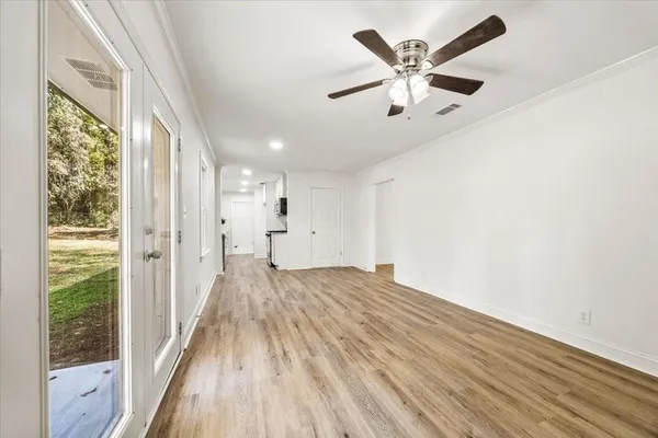 a view of empty room with wooden floor and fan