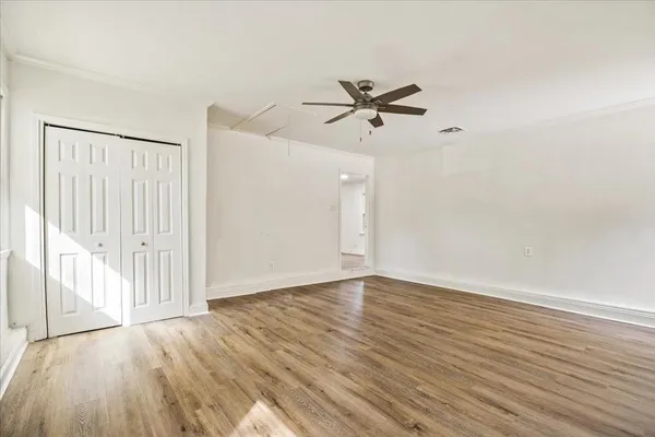 a view of empty room with wooden floor and ceiling fan