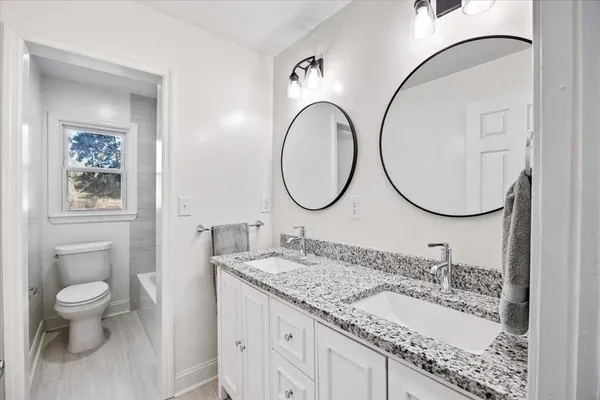 a bathroom with a granite countertop double vanity sink and a mirror