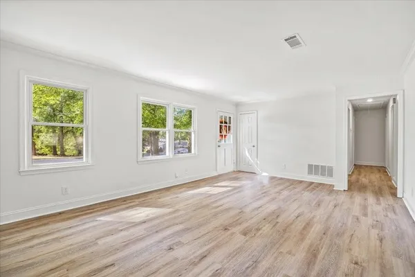 a view of an empty room with wooden floor and a window