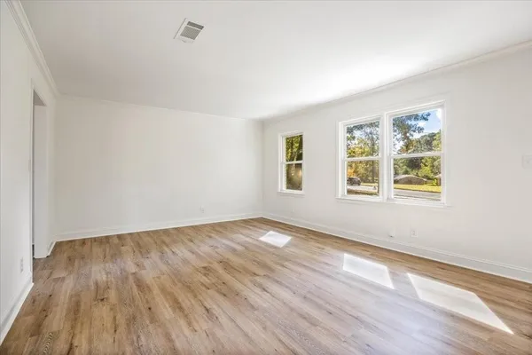 an empty room with wooden floor and windows
