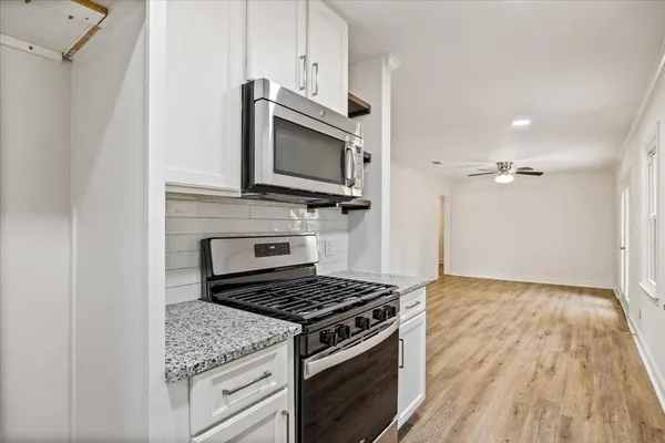 a kitchen with granite countertop a stove and a microwave