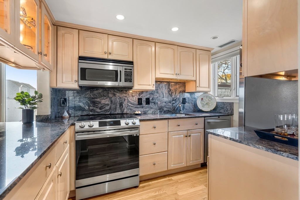 55 Brackett Place, Unit D Marblehead, MA 01945 - Photo 9 of 34 a kitchen with granite countertop wooden cabinets stainless steel appliances and a counter space