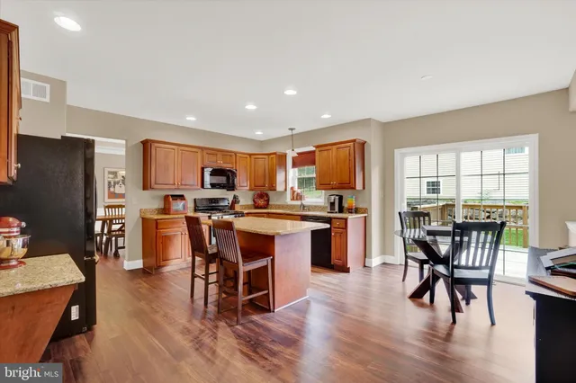 a kitchen with stainless steel appliances granite countertop dining table chairs refrigerator and sink