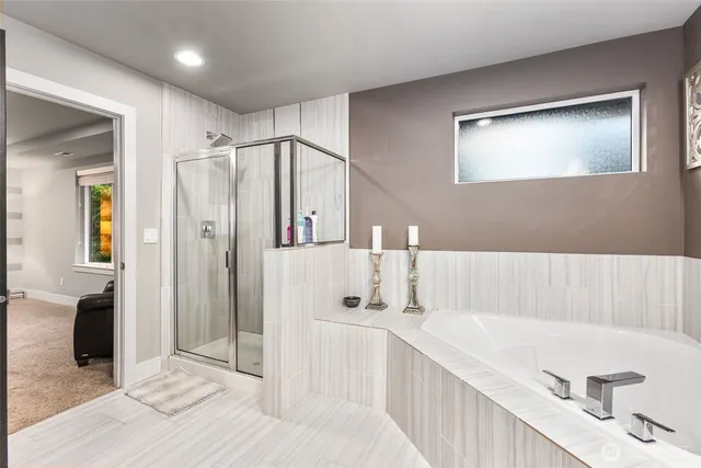 a bathroom with a tub a mirror and a shower