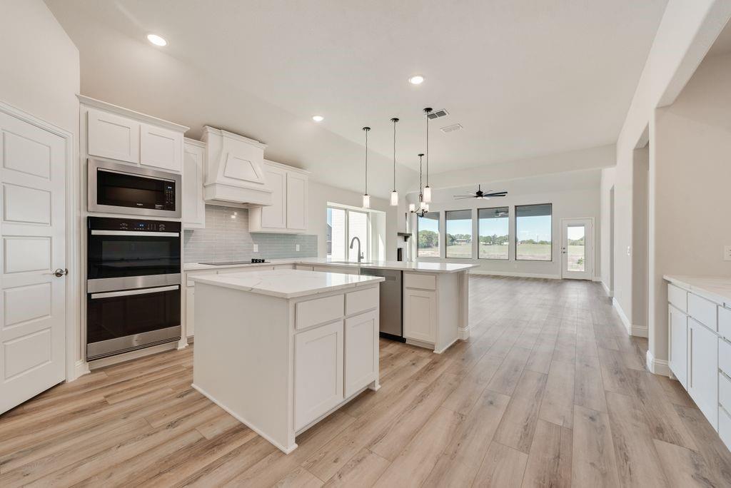1036 Monaco Court Springtown, TX 76082 - Photo 4 of 12 a kitchen with kitchen island wooden floors appliances and cabinets
