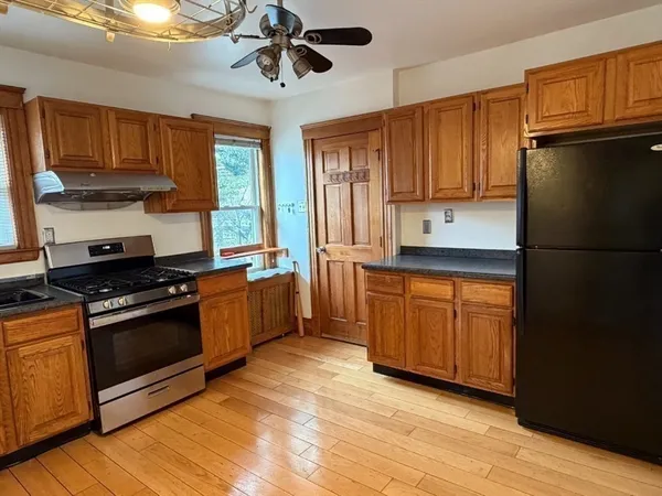 a kitchen with stainless steel appliances granite countertop a refrigerator a sink dishwasher a stove and white countertops with wooden floor