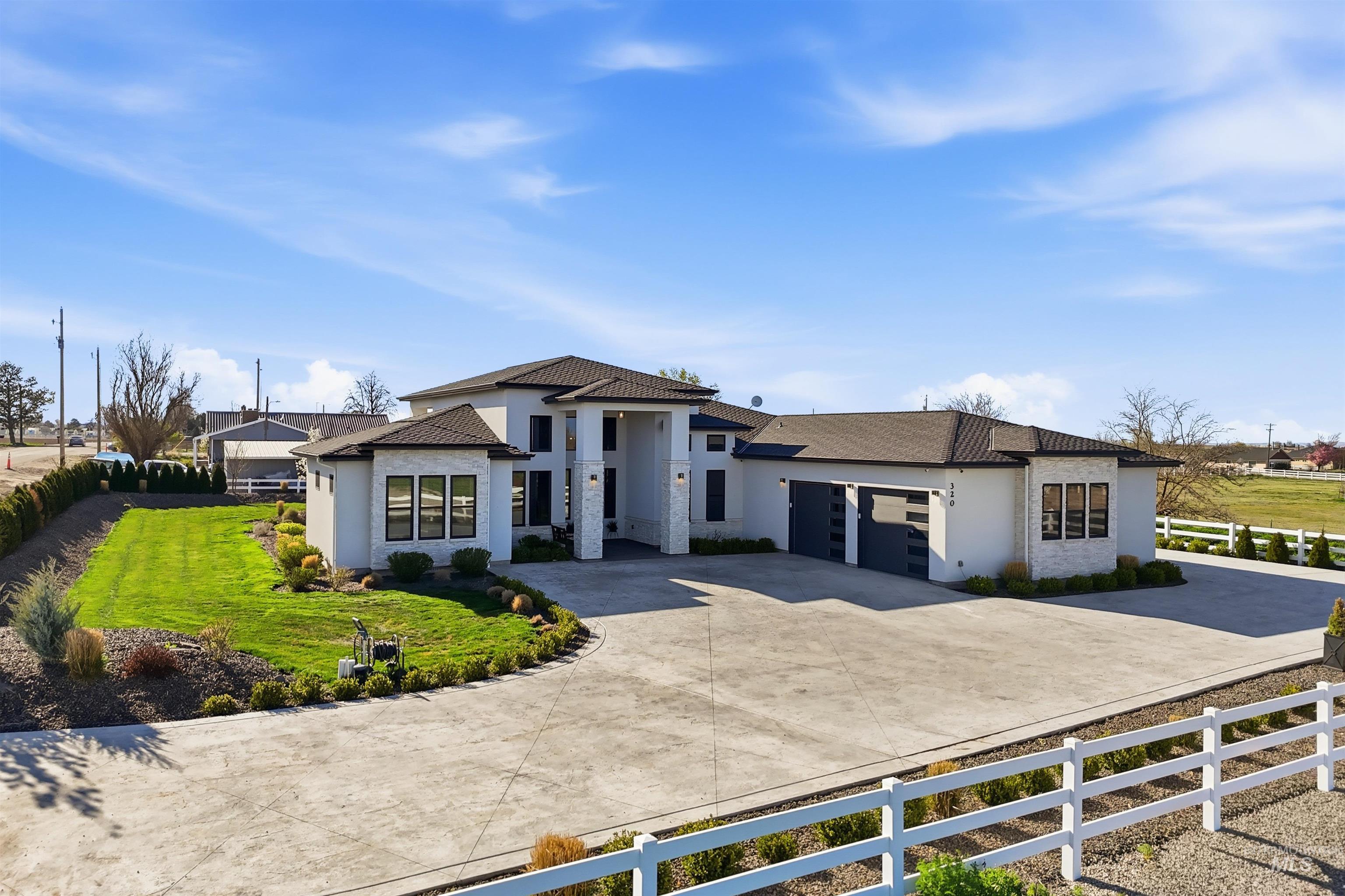 View of front of property with a fenced front yard, stucco siding, driveway, an attached garage, and stone siding