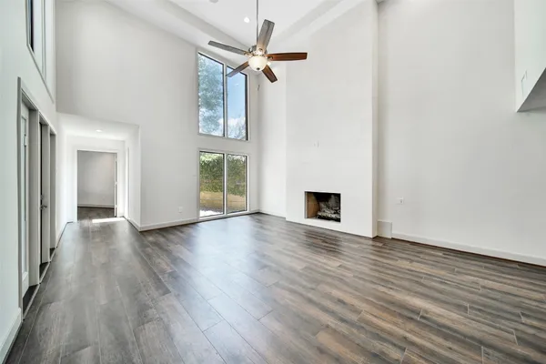 a view of an empty room with wooden floor and a ceiling fan