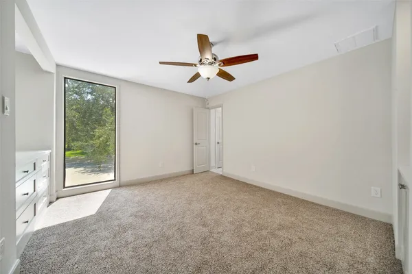 an empty room with chandelier fan and windows