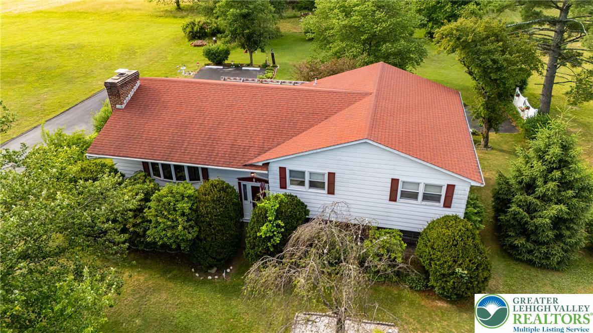 678 Interchange Road Kresgeville, PA 18333 - Photo 9 of 45 An inviting residence set amidst lush green landscaping and mature trees, featuring a prominent red roof.