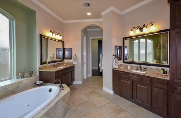 a spacious bathroom with a double vanity sink large mirror and bathtub