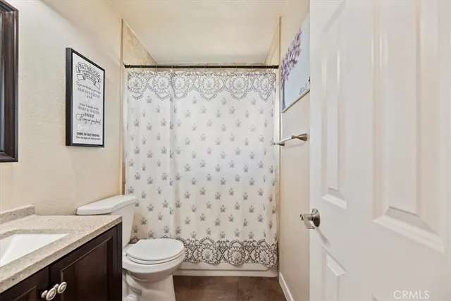 a bathroom with a granite countertop toilet and a shower curtain