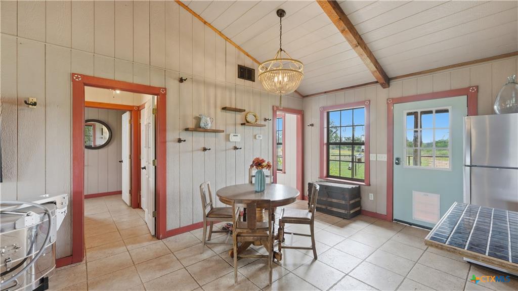 127 Offer Llano, TX 78643 - Photo 7 of 40 Open-concept space featuring tile flooring, vertical plank walls, and an exposed beam vaulted ceiling