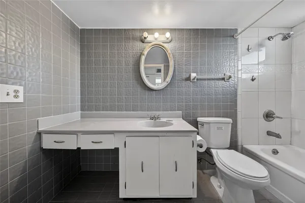 a bathroom with a granite countertop sink a toilet and shower