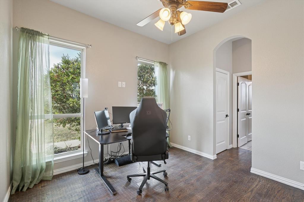 542 Pierce Road Red Oak, TX 75154 - Photo 25 of 27 Spacious room featuring wood-finish flooring, two large windows, an arched doorway, and a ceiling fan with integrated lighting