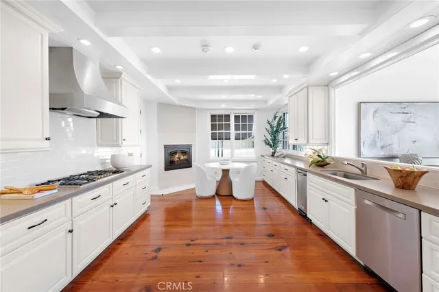 a large kitchen with stainless steel appliances granite countertop a refrigerator a stove top oven a dining table and chairs with wooden floor