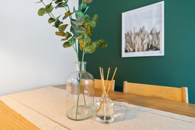 a vase of flowers sitting on a table with a potted plant
