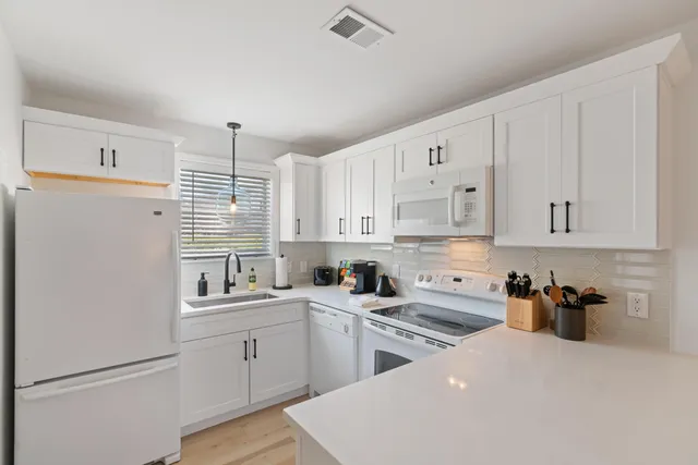 a kitchen with white cabinets and white appliances