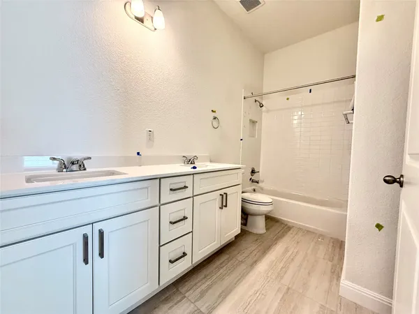 a spacious bathroom with a double vanity sink toilet mirror and bathtub