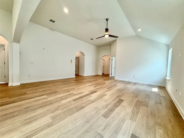 an empty room with wooden floor and windows
