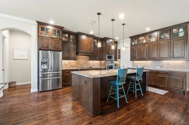 a kitchen with stainless steel appliances kitchen island granite countertop a table chairs sink and cabinets