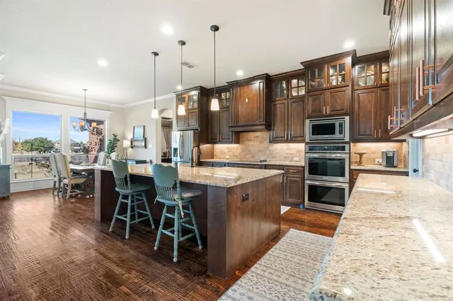 a kitchen with stainless steel appliances granite countertop a stove and a wooden floors