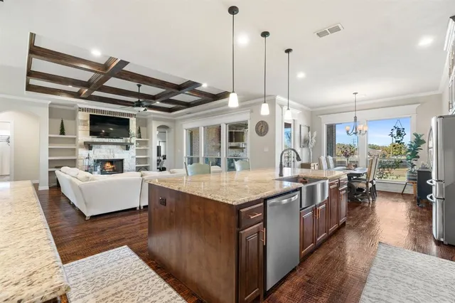 a kitchen with stainless steel appliances granite countertop a sink a stove and a wooden floors