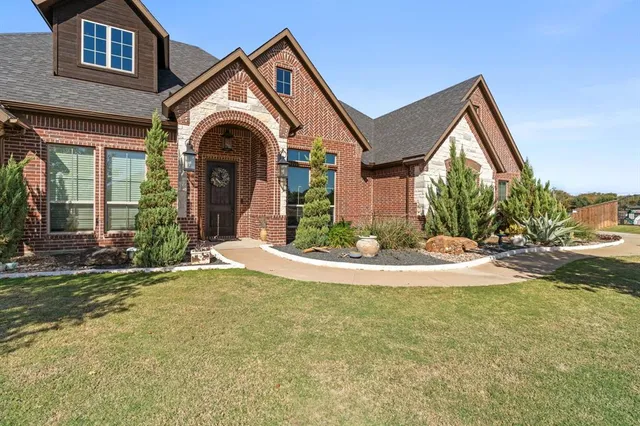 a view of a house with a yard and large tree
