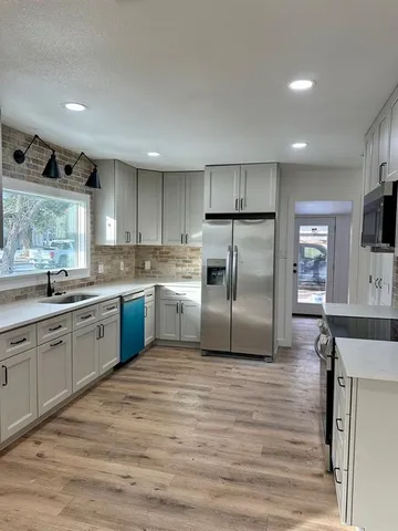 a kitchen with granite countertop a refrigerator sink and cabinets