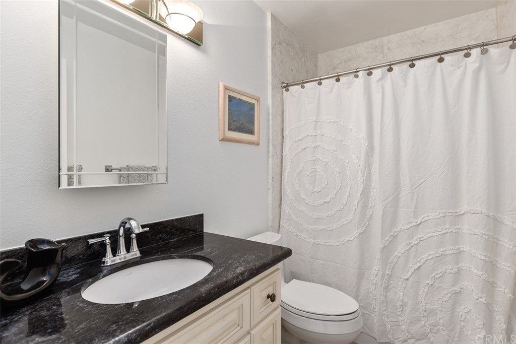 10 Mandrake Way Irvine, CA 92612 - Photo 20 of 35 a bathroom with a granite countertop sink toilet a mirror and shower curtain