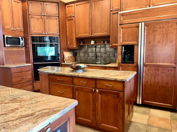 a kitchen with stainless steel appliances granite countertop wooden cabinets a refrigerator and a sink
