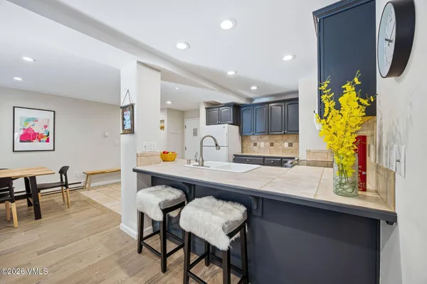 a kitchen with stainless steel appliances granite countertop a table chairs refrigerator and sink
