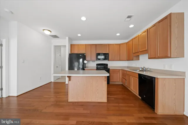 a kitchen with a refrigerator a stove top oven a sink and dishwasher with wooden floor