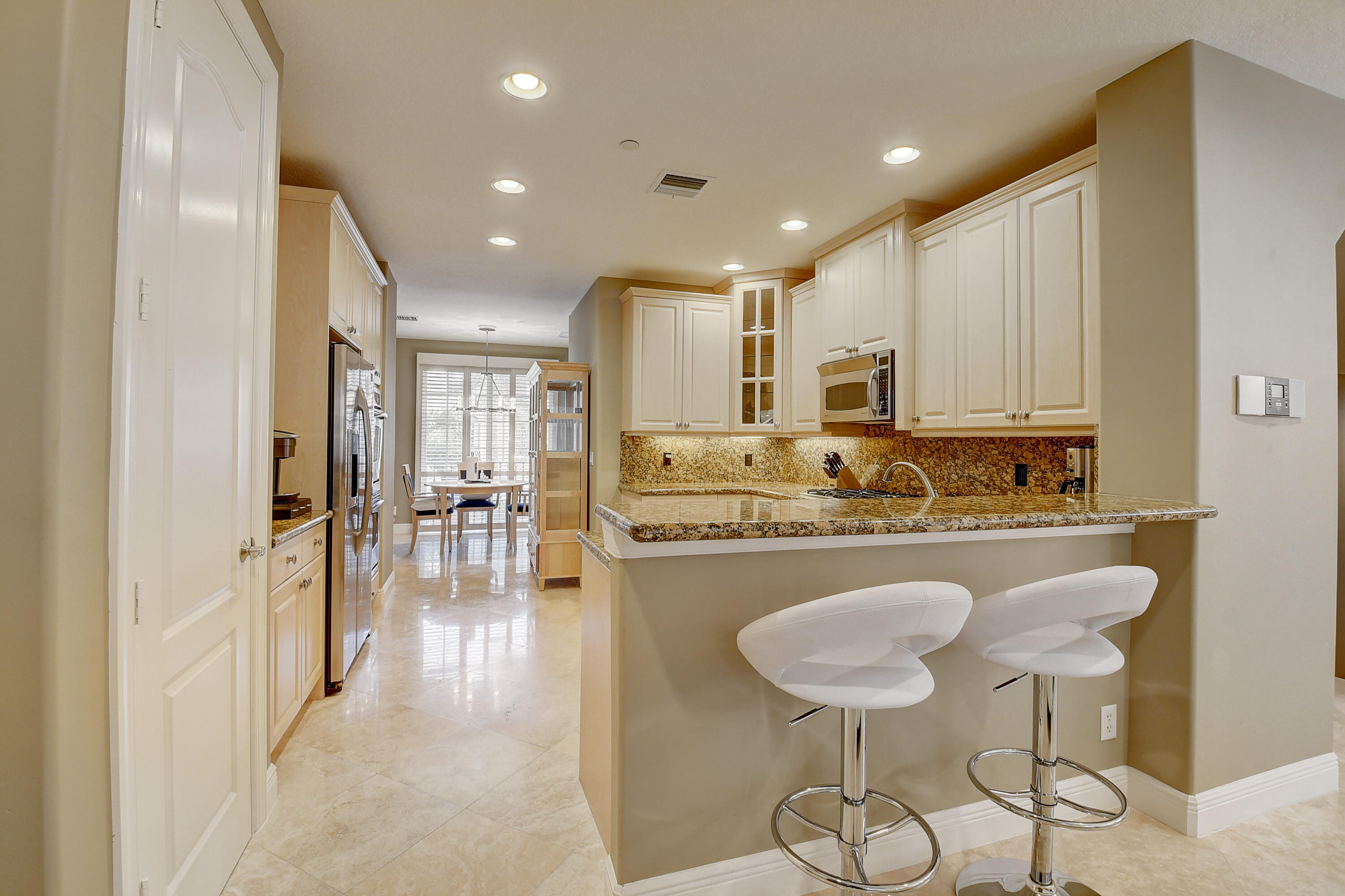 5645 Northeast Trieste Way Boca Raton, FL 33487 - Photo 12 of 38 a kitchen with stainless steel appliances granite countertop a stove a sink a refrigerator and white cabinets with wooden floor