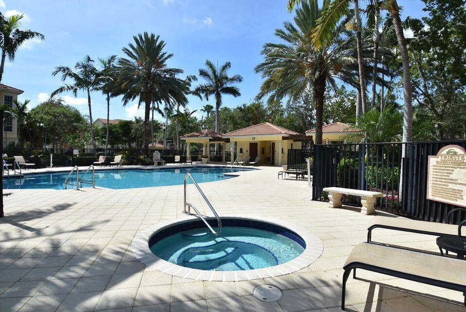 5645 Northeast Trieste Way Boca Raton, FL 33487 - Photo 36 of 38 a swimming pool with a lawn chairs under palm trees