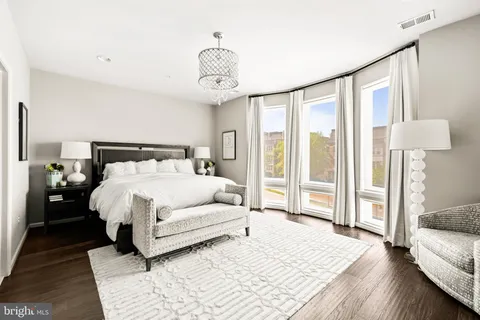 a bedroom with a bed a desk and chair with wooden floor