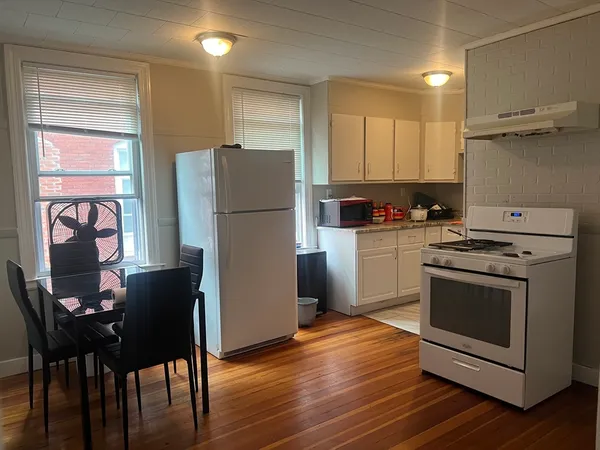 a kitchen with a stove a refrigerator and a dining table with wooden floor