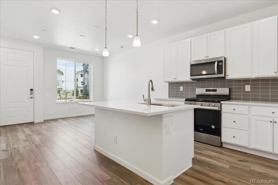 a kitchen with granite countertop a stove a sink and a microwave